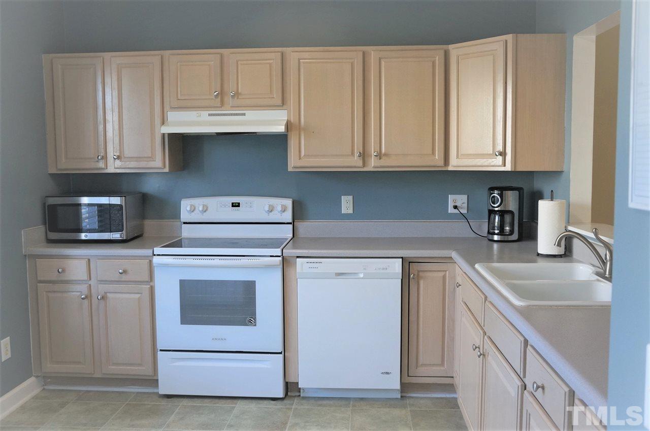 9204 Grassington Way Raleigh, NC 27615 - Photo 9 of 29 a kitchen with granite countertop white cabinets and white appliances