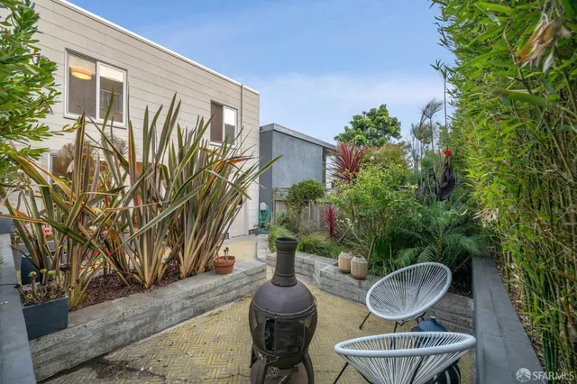a view of a backyard with table and chairs potted plants and palm tree