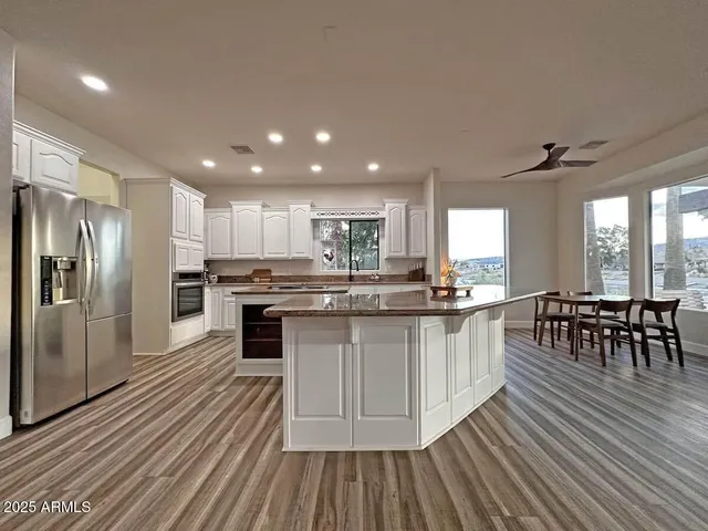 a kitchen with stainless steel appliances granite countertop a stove refrigerator and a dining table with wooden floor