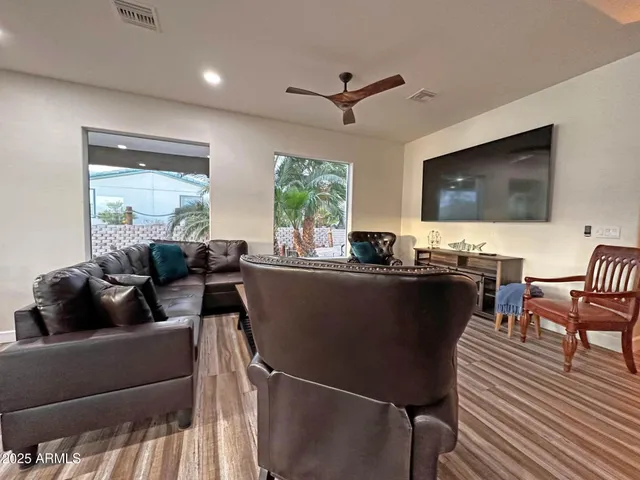 a living room with furniture floor to ceiling window hardwood floor and a flat screen tv