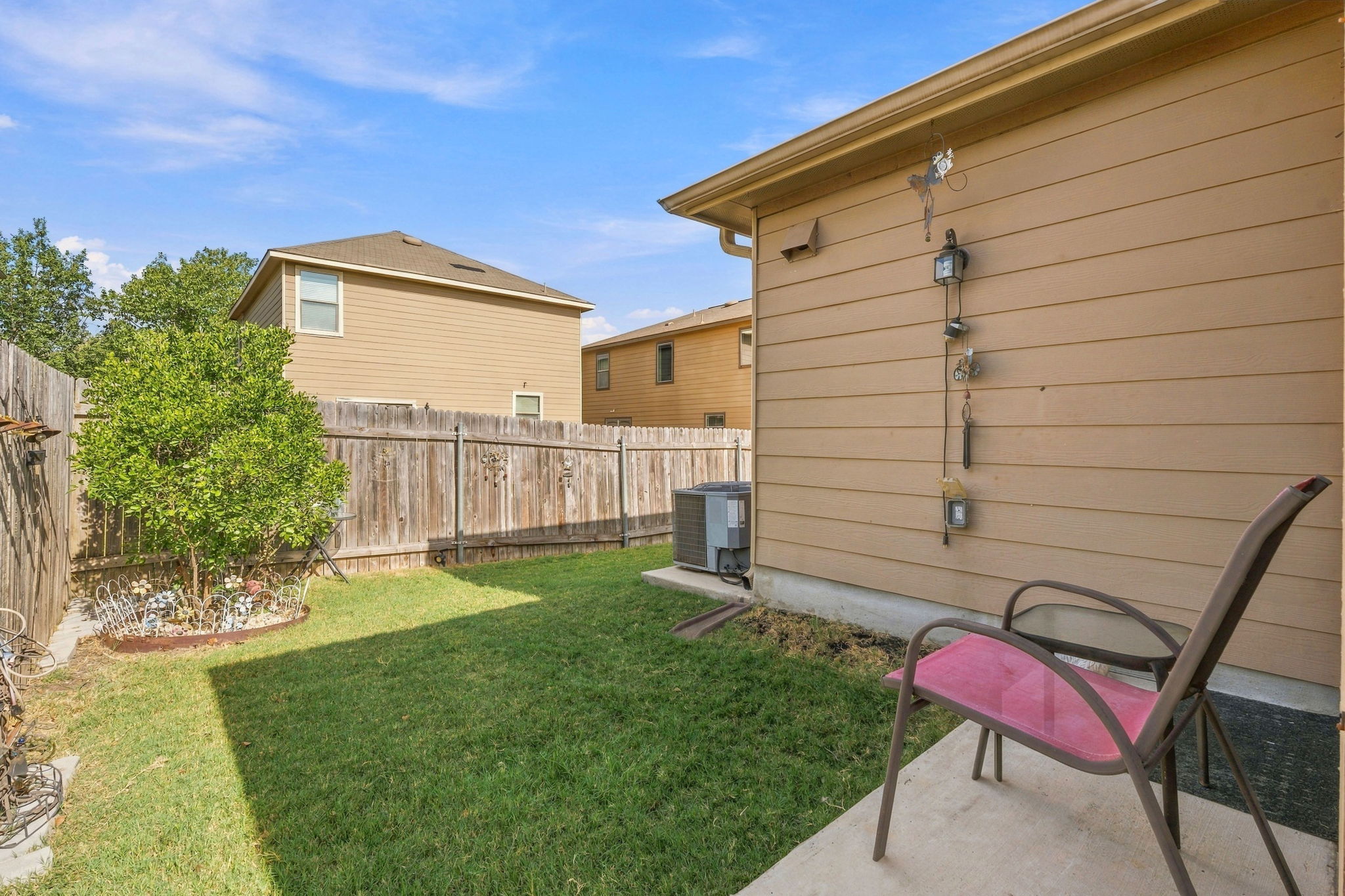 9004 Wiley Way Austin, TX 78747 - Photo 26 of 39 A private grassy backyard bordered by a tall wooden privacy fence under sunny skies.