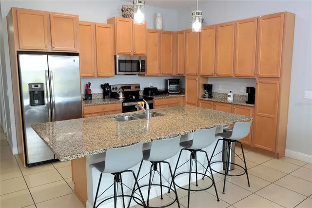 a kitchen with stainless steel appliances granite countertop a table chairs microwave and sink