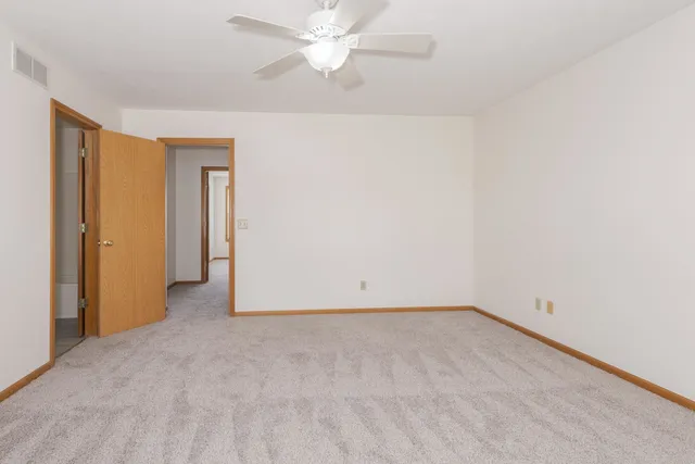 an empty room with a ceiling fan and a window