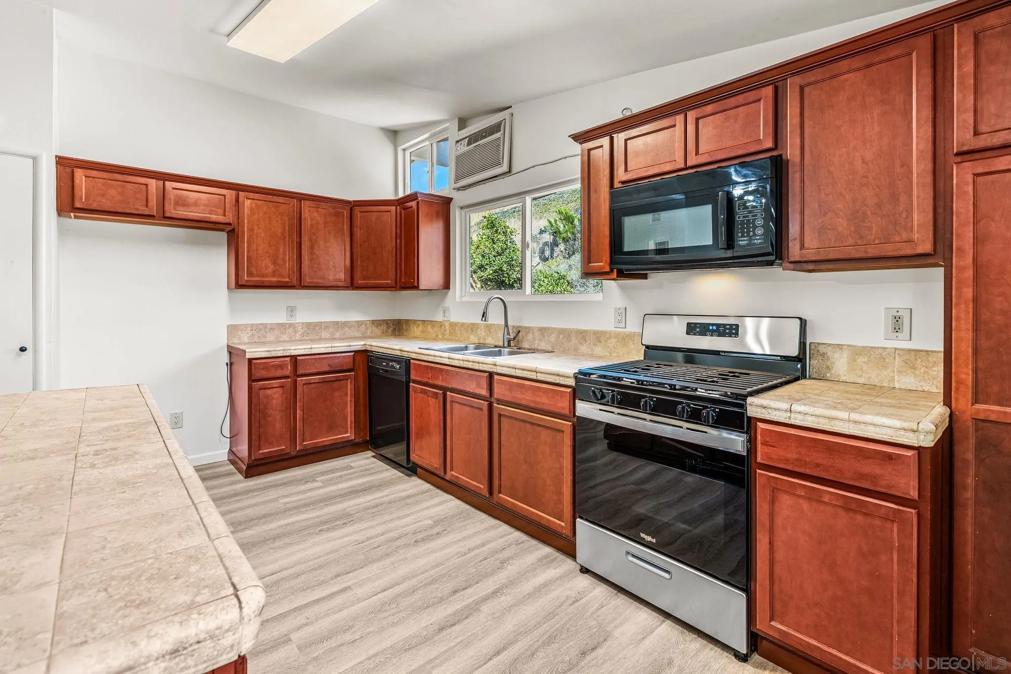 13323 Frame Road Poway, CA 92064 - Photo 7 of 30 a kitchen with stainless steel appliances granite countertop a stove top oven a sink dishwasher and a microwave oven with large wooden cabinets