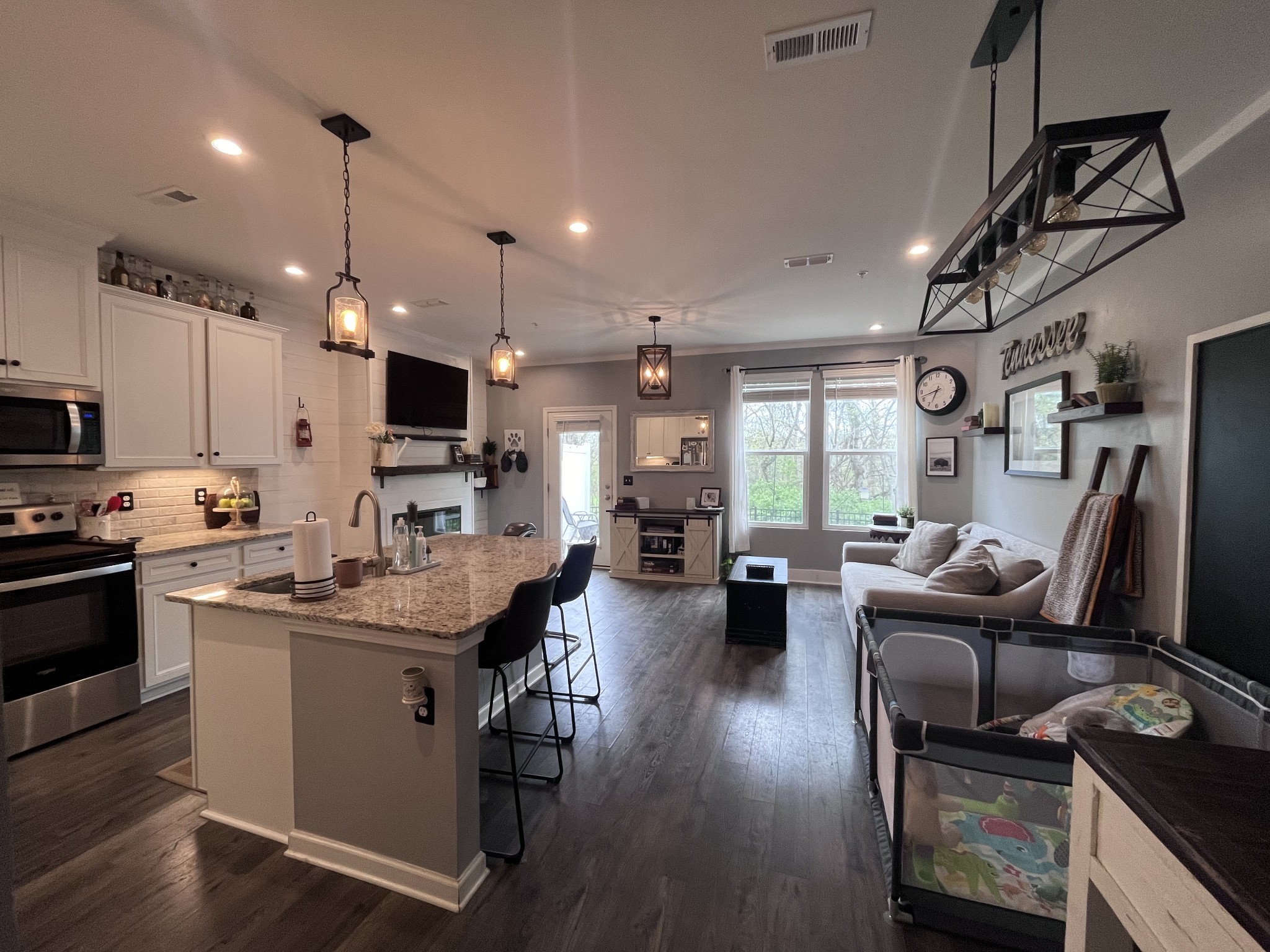 a kitchen with stainless steel appliances kitchen island granite countertop a stove a refrigerator a sink dishwasher a dining table and chairs with wooden floor