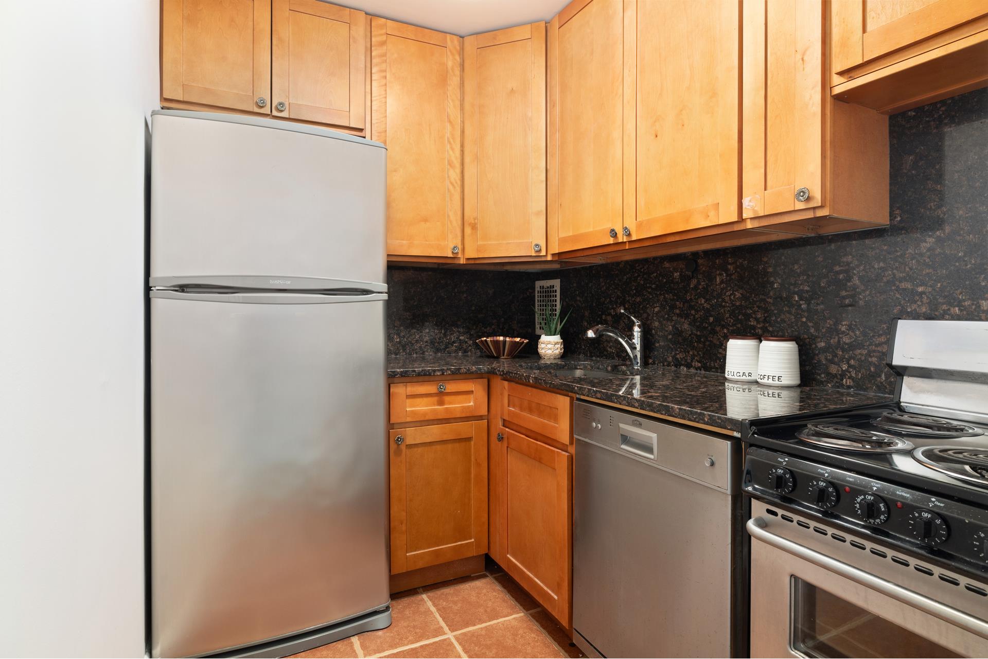 244 Madison Avenue, Unit 12F Manhattan, NY 10016 - Photo 4 of 11 a kitchen with stainless steel appliances granite countertop a refrigerator a sink and white cabinets