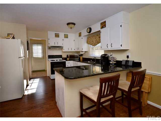 7309 Mine Valley Road Raleigh, NC 27615 - Photo 6 of 15 a kitchen with stainless steel appliances granite countertop a refrigerator a stove a sink dishwasher and white cabinets with wooden floor