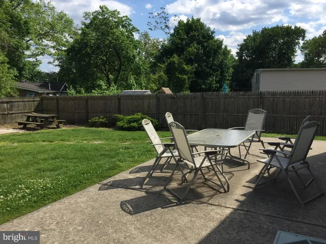 a view of a backyard with table and chairs potted plants and a tree