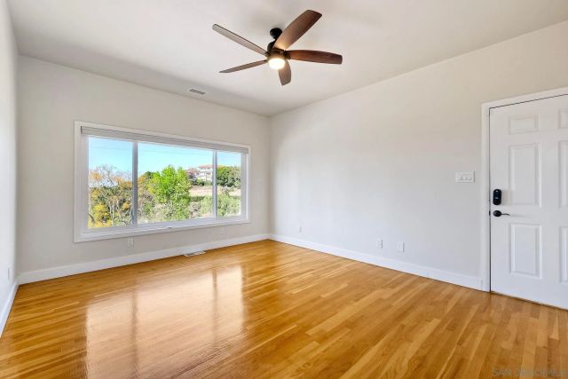 a view of empty room with wooden floor and fan