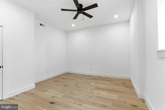 an empty room with a ceiling fan and window