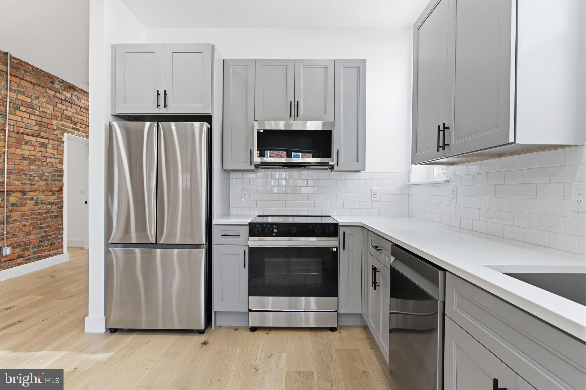 2724-26 East Somerset Street, Unit 1 Philadelphia, PA 19134 - Photo 6 of 21 a kitchen with granite countertop a refrigerator stove and microwave