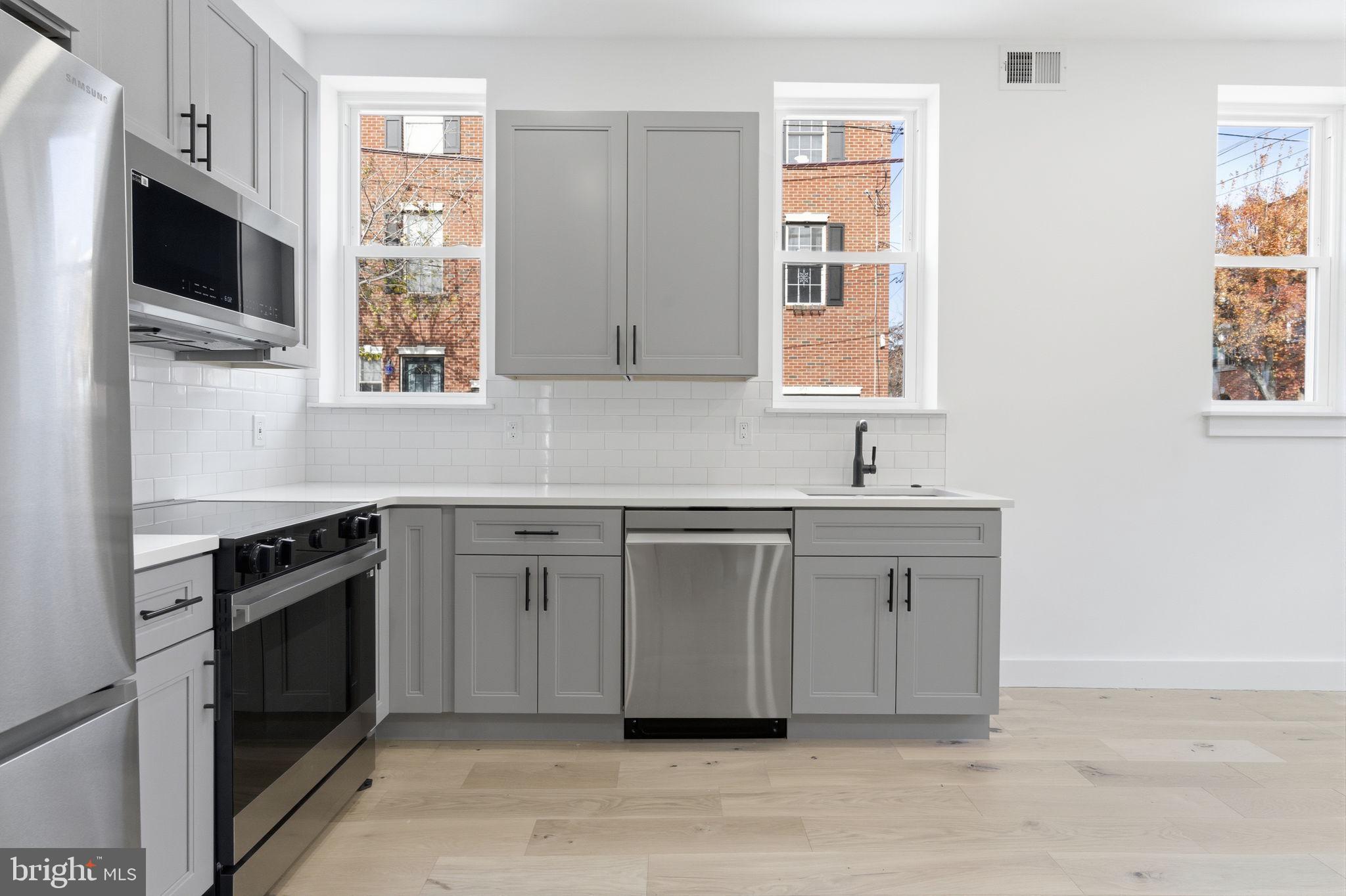 2724-26 East Somerset Street, Unit 1 Philadelphia, PA 19134 - Photo 7 of 21 a kitchen with stainless steel appliances granite countertop a stove a sink and a microwave