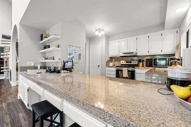 a kitchen with stainless steel appliances granite countertop a sink a stove and a counter space