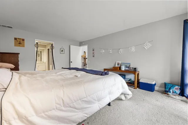 a bed room with a bed mirror and a chair