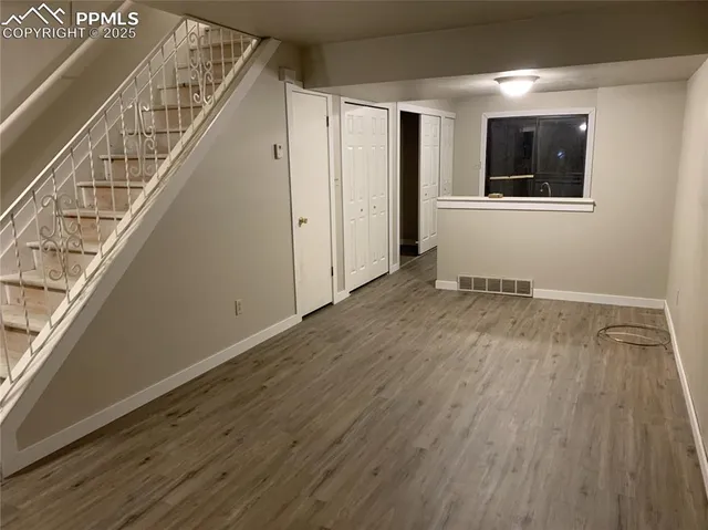 a view of an empty room with wooden floor and stairs