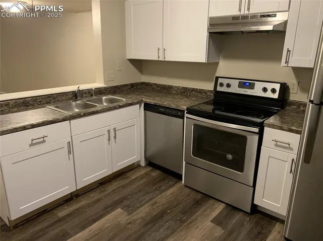 a kitchen with granite countertop cabinets stainless steel appliances and wooden floor
