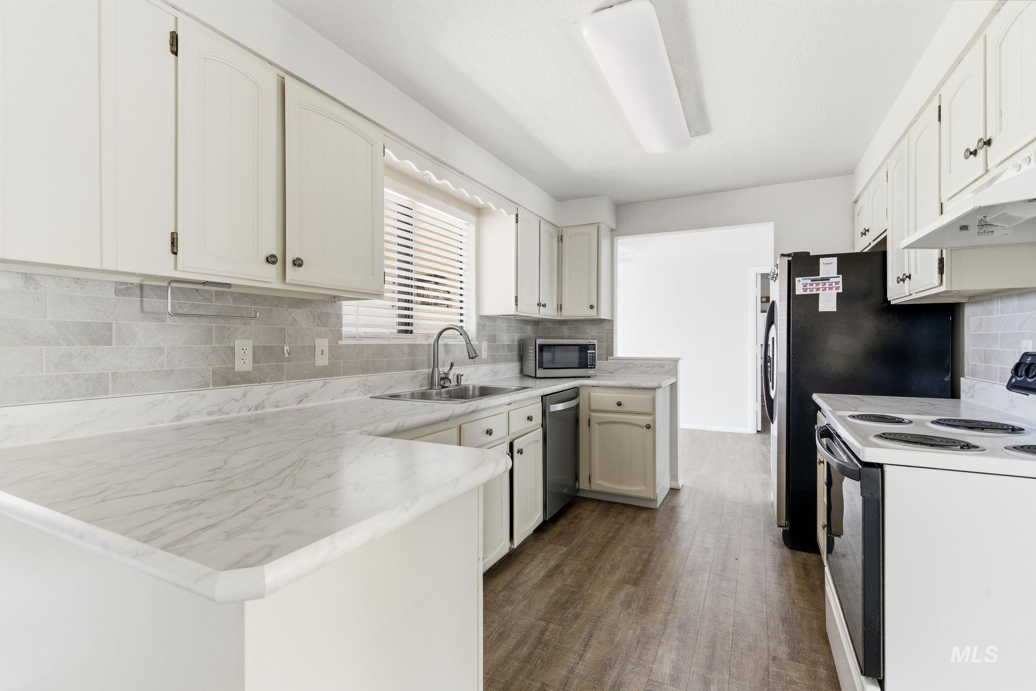3911 South Constitution Way Boise, ID 83706 - Photo 14 of 40 Kitchen with stainless steel appliances, light countertops, a peninsula, backsplash, and dark wood finished floors