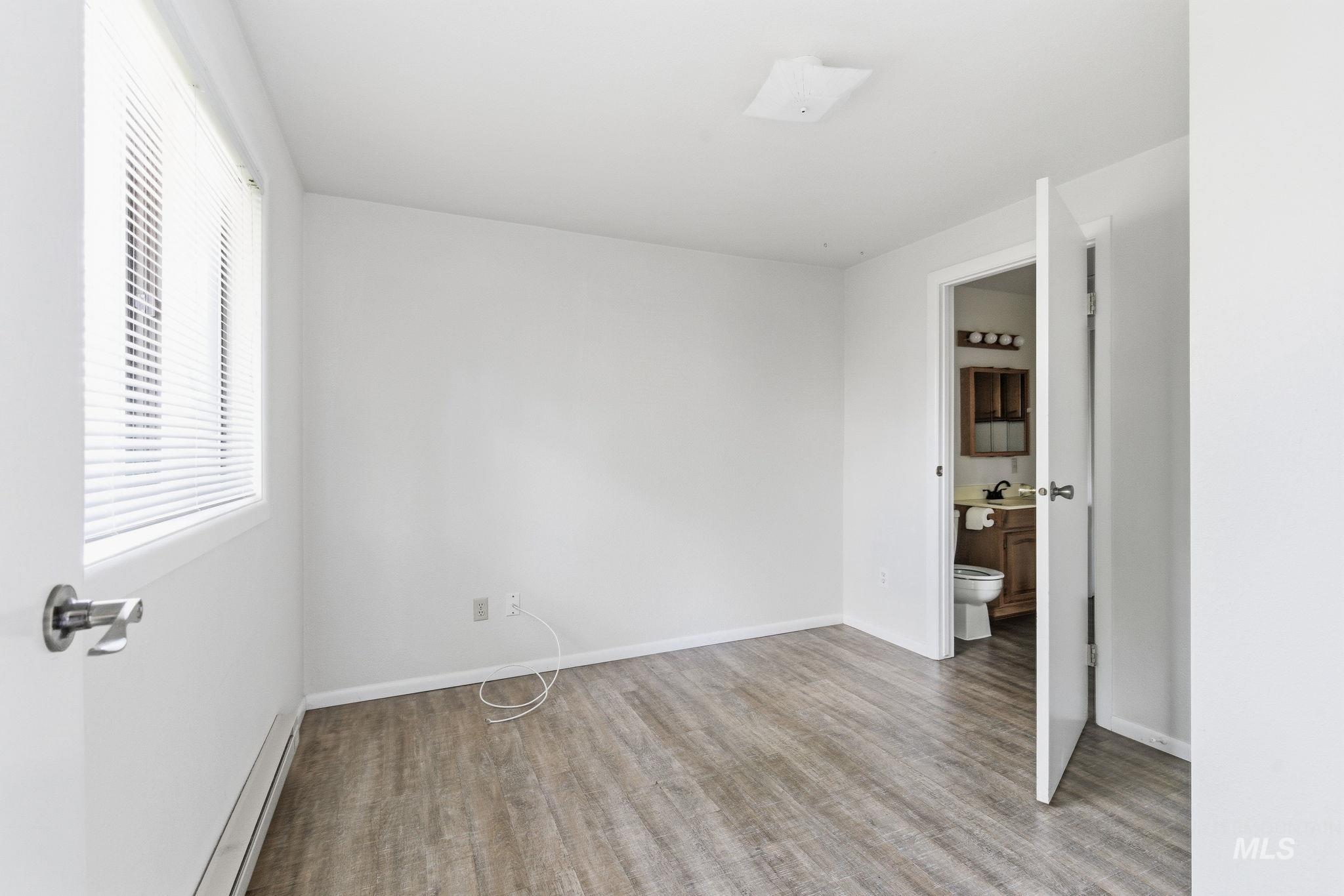 3911 South Constitution Way Boise, ID 83706 - Photo 23 of 40 Unfurnished bedroom featuring a baseboard heating unit, light wood-type flooring, and connected bathroom