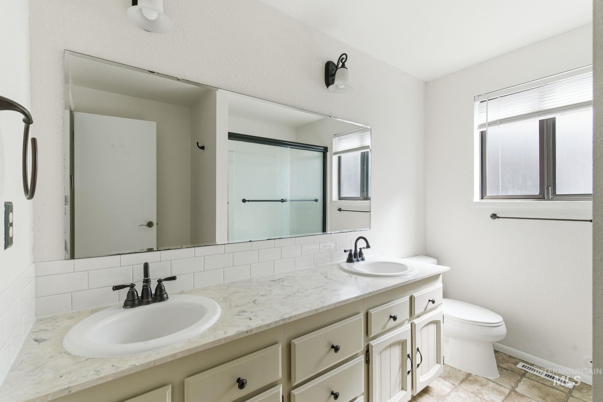 3911 South Constitution Way Boise, ID 83706 - Photo 34 of 40 Bathroom featuring double vanity, tasteful backsplash, and a shower stall
