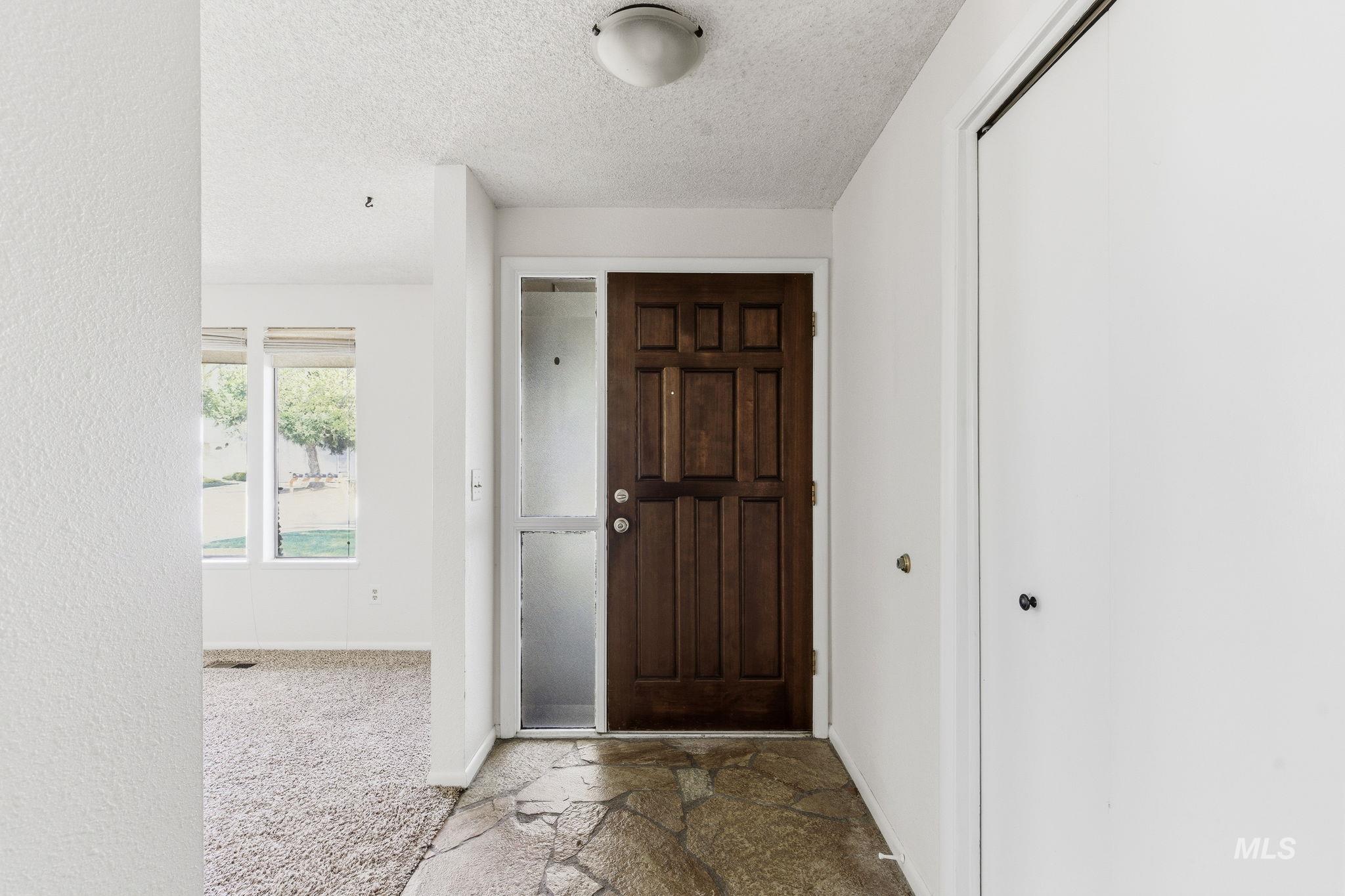 3911 South Constitution Way Boise, ID 83706 - Photo 4 of 40 Foyer entrance featuring a textured ceiling, stone finish flooring, and carpet