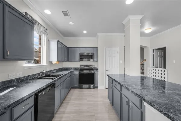 a kitchen with stainless steel appliances granite countertop a sink a stove and a refrigerator