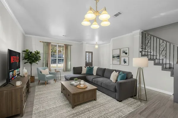 a living room with furniture a chandelier and a flat screen tv
