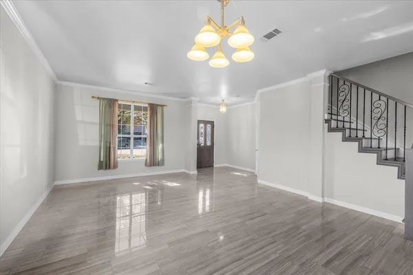 a view of an empty room with wooden floor and windows
