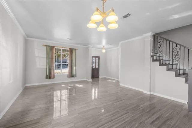 a view of an empty room with wooden floor and windows