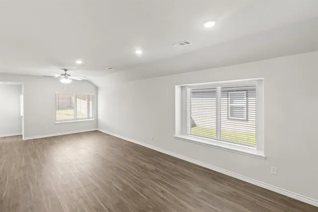 an empty room with wooden floor and windows