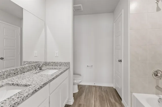a bathroom with a granite countertop sink a toilet and shower