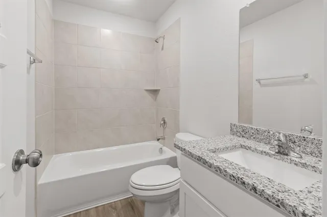 a bathroom with a granite countertop sink a toilet and shower