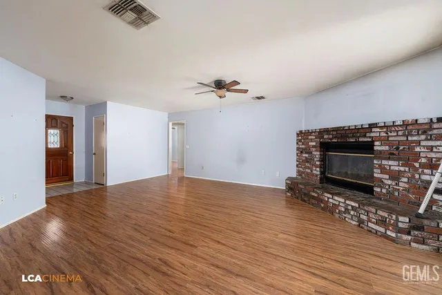a view of an empty room with a fireplace and wooden floor