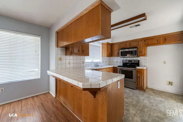 a kitchen with stainless steel appliances kitchen island granite countertop a sink stove and refrigerator