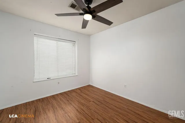 an empty room with a window and a ceiling fan