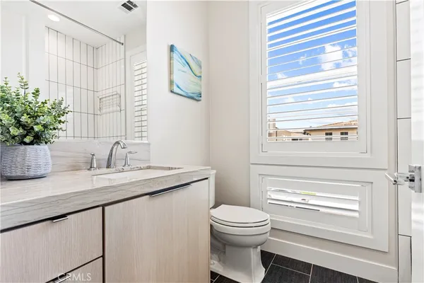 a bathroom with a granite countertop sink mirror vanity and toilet