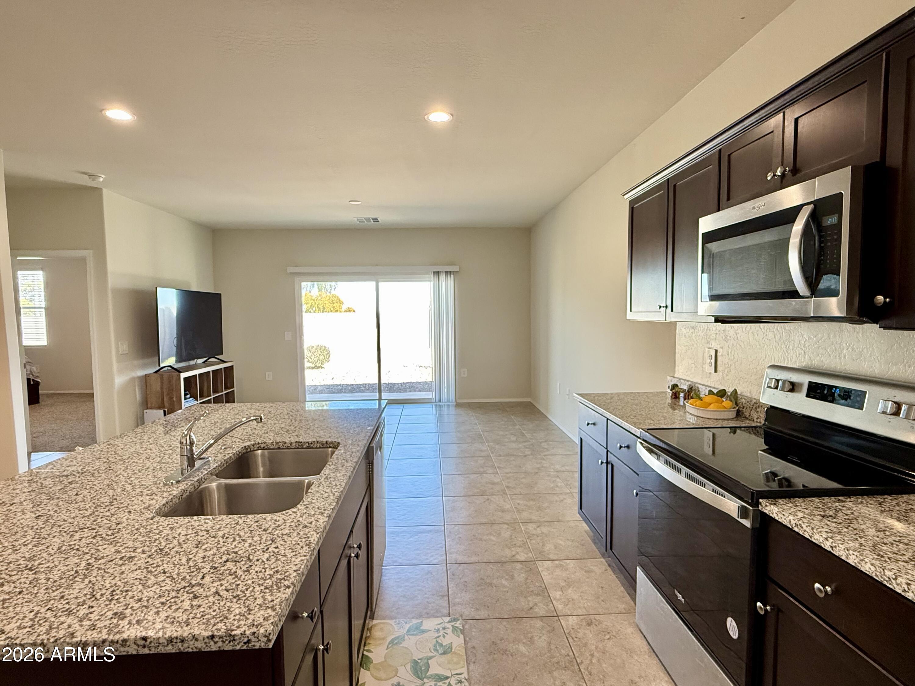 2207 South 46th Street Coolidge, AZ 85128 - Photo 13 of 35 a kitchen with granite countertop stainless steel appliances a sink stove and refrigerator