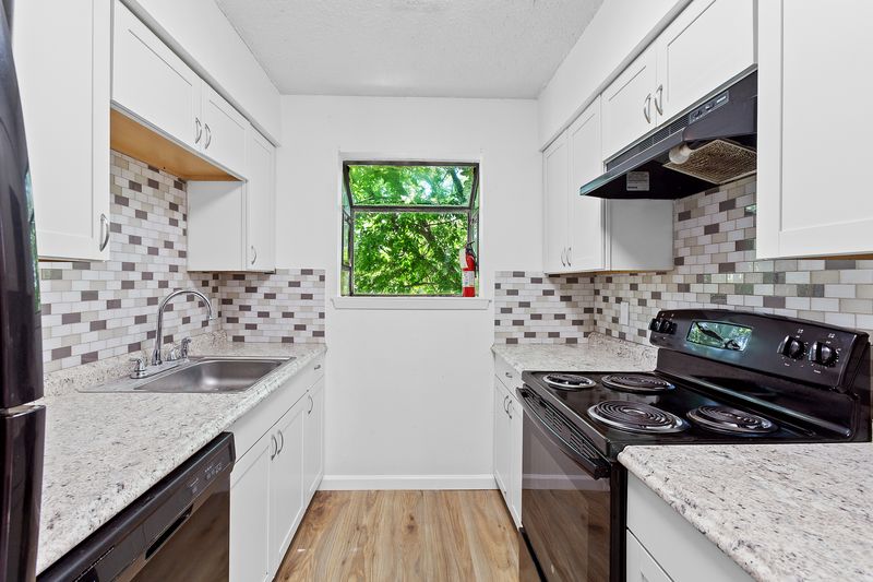1907 West Loop Austin, TX 78758 - Photo 7 of 31 a kitchen with granite countertop a sink a stove and wooden cabinets