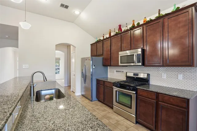 a kitchen with stainless steel appliances granite countertop a stove a sink and a microwave