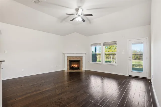 an empty room with wooden floor chandelier fan and windows