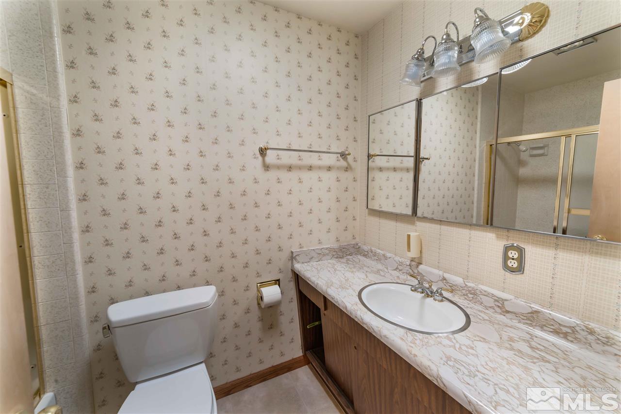 1585 Surf Way Reno, NV 89503 - Photo 8 of 16 a bathroom with a granite countertop sink a toilet and a mirror