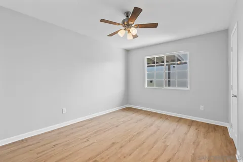 an empty room with a window and a ceiling fan