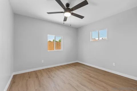 an empty room with wooden floor and a ceiling fan