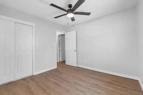 an empty room with wooden floor and a ceiling fan
