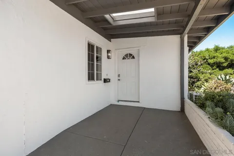 a view of an empty room with wooden floor and a mirror