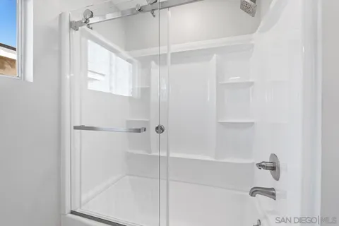 a view of an empty room with wooden floor and window