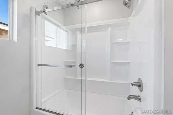 a view of an empty room with wooden floor and window