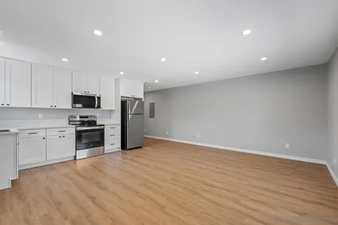 a view of an empty room with wooden floor and closet