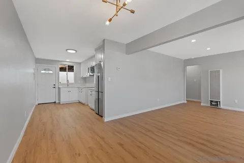 a view of an empty room with window and wooden floor