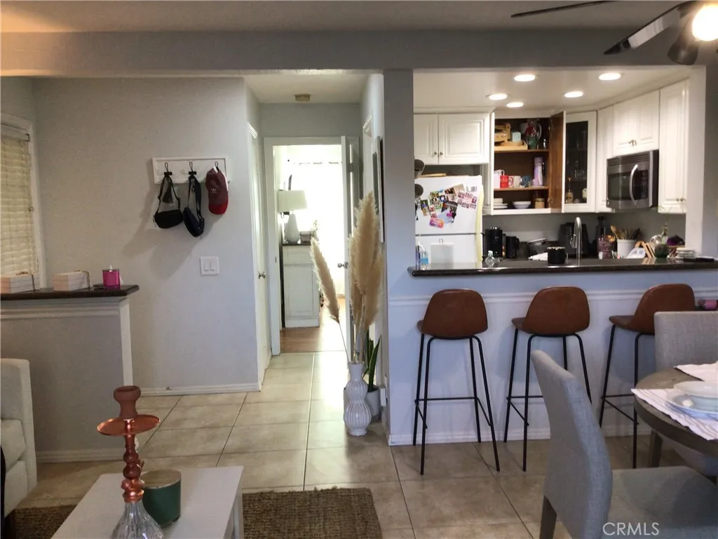 26161 Del Rey, Unit C Mission Viejo, CA 92691 - Photo 3 of 11 a kitchen with stainless steel appliances granite countertop a stove a refrigerator a sink a dining table and chairs with wooden floor