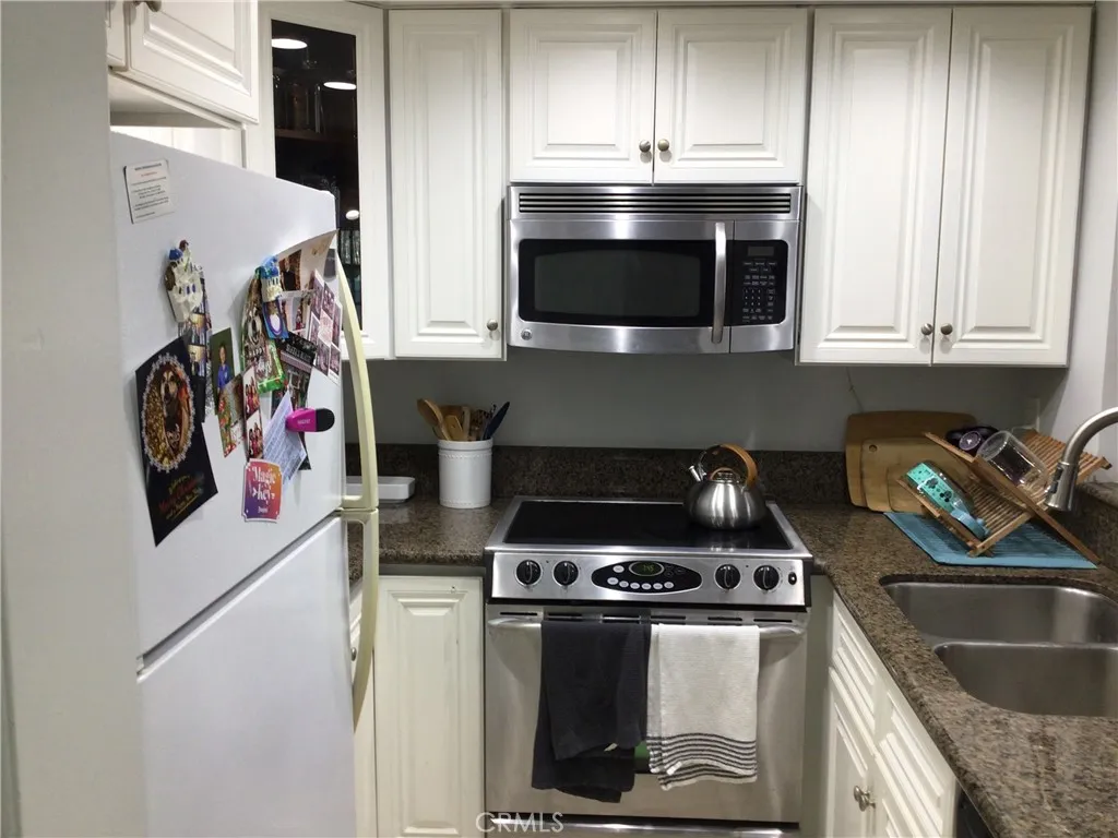 26161 Del Rey, Unit C Mission Viejo, CA 92691 - Photo 4 of 11 a kitchen with stainless steel appliances granite countertop a stove and a microwave